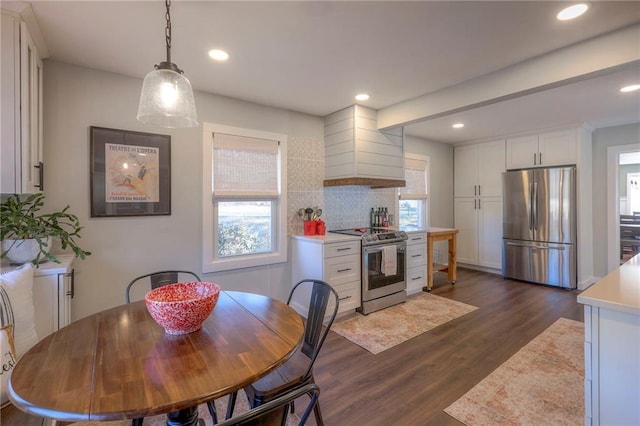 kitchen with pendant lighting, premium range hood, appliances with stainless steel finishes, dark hardwood / wood-style flooring, and white cabinetry