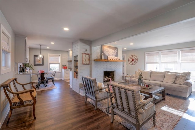 living room featuring a brick fireplace and dark wood-type flooring