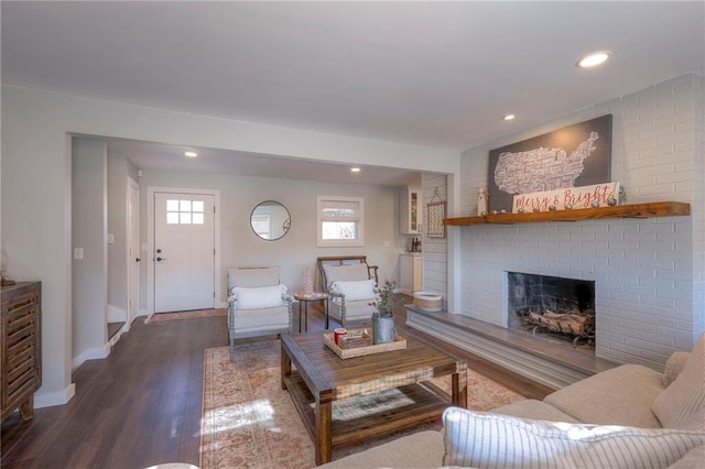 living room featuring a brick fireplace and dark wood-type flooring