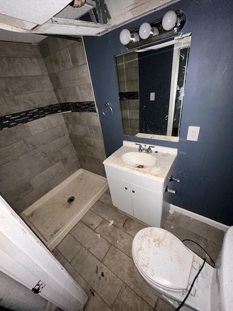 bathroom featuring vanity, toilet, and a tile shower