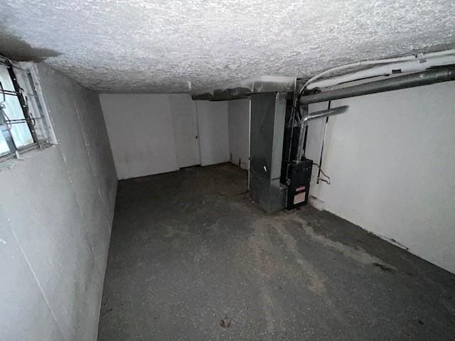 basement featuring heating unit and a textured ceiling