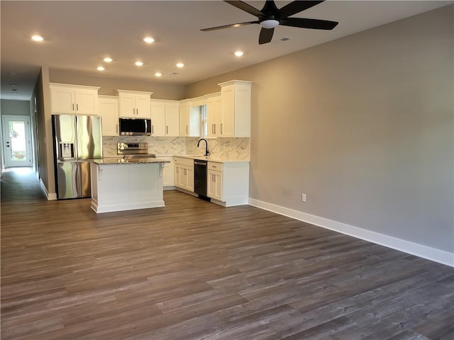 kitchen featuring white cabinets, a center island, stainless steel appliances, and dark wood-type flooring