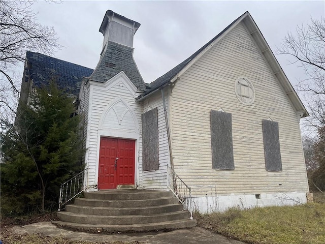 view of front of home with entry steps, crawl space, and a chimney