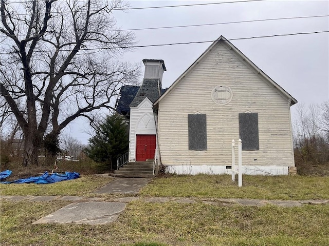 view of side of home featuring entry steps, crawl space, and a chimney