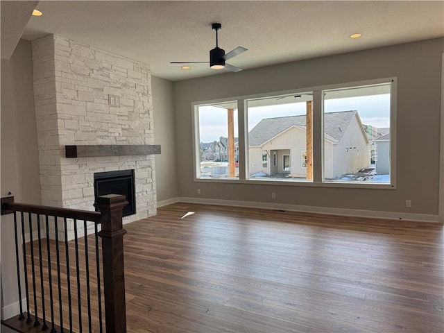 unfurnished living room with hardwood / wood-style floors, a stone fireplace, and plenty of natural light