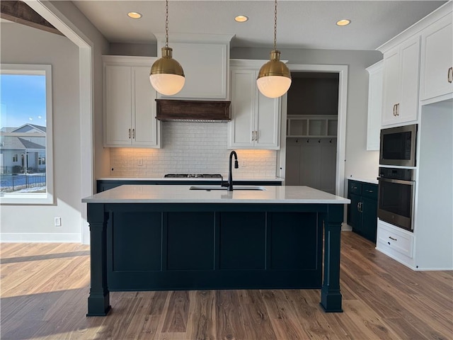 kitchen featuring built in microwave, sink, white cabinets, oven, and hanging light fixtures