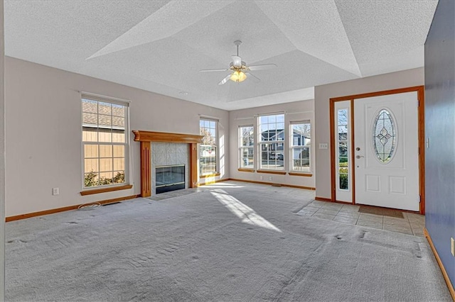 carpeted entrance foyer featuring a tile fireplace, a textured ceiling, and ceiling fan