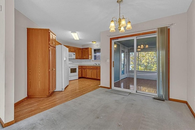 kitchen with a notable chandelier, decorative light fixtures, light hardwood / wood-style floors, and white appliances