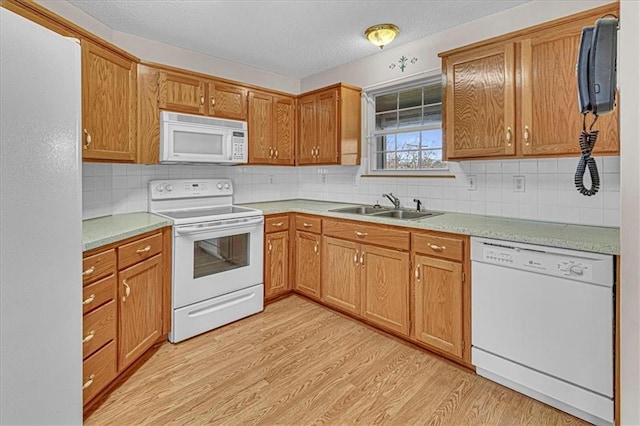 kitchen with white appliances, backsplash, sink, light wood-type flooring, and a textured ceiling