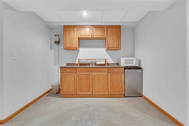 kitchen with refrigerator, light colored carpet, and sink