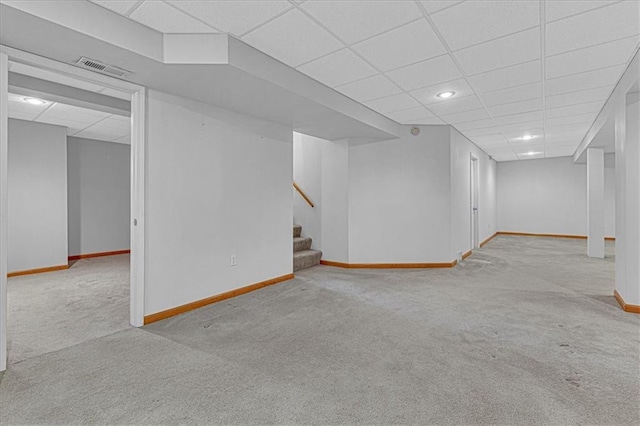 basement featuring a drop ceiling and light carpet