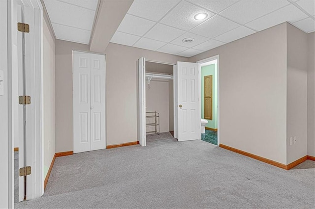 unfurnished bedroom with a paneled ceiling and light carpet