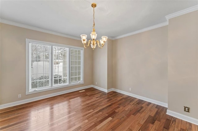 empty room featuring hardwood / wood-style floors, crown molding, and a notable chandelier