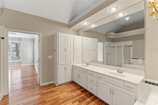 bathroom with vanity, a shower with shower door, lofted ceiling, and wood-type flooring