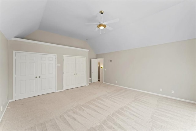 unfurnished bedroom featuring light carpet, vaulted ceiling, ceiling fan, and multiple closets