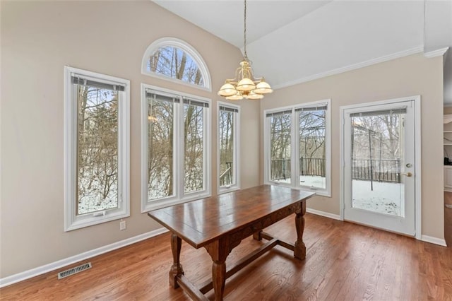 dining area with an inviting chandelier, hardwood / wood-style flooring, and lofted ceiling