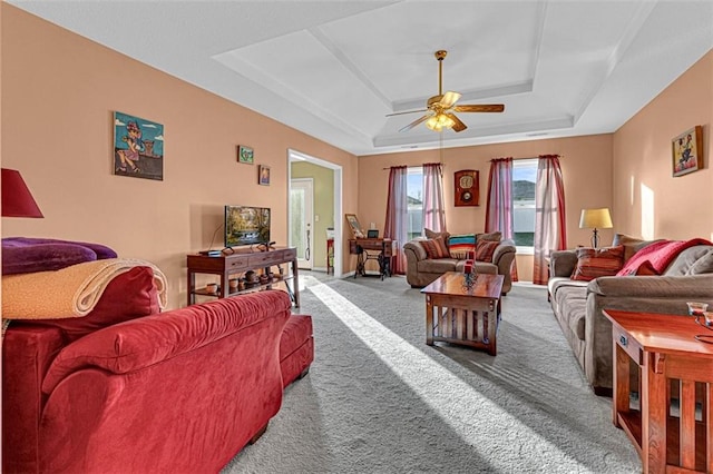 carpeted living room featuring ceiling fan and a raised ceiling