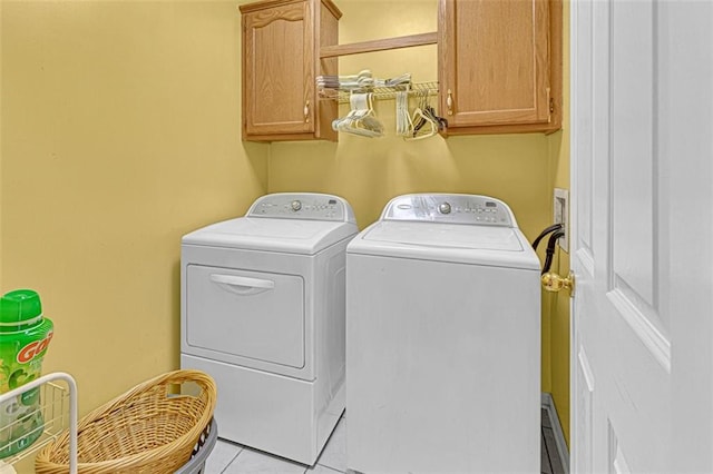 laundry area with separate washer and dryer, light tile patterned floors, and cabinets