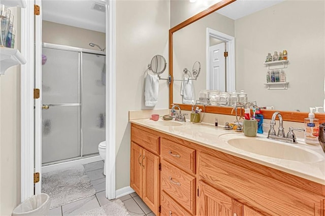 bathroom featuring tile patterned flooring, vanity, an enclosed shower, and toilet