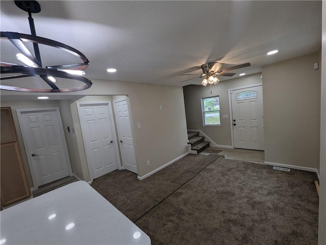 carpeted foyer entrance with ceiling fan and a textured ceiling