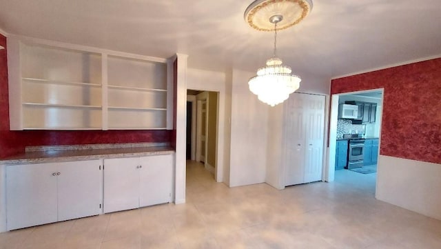 kitchen featuring backsplash, a notable chandelier, stainless steel range oven, white cabinetry, and hanging light fixtures