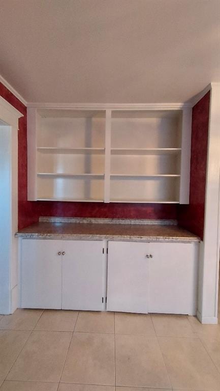 kitchen featuring white cabinets, light tile patterned floors, and crown molding