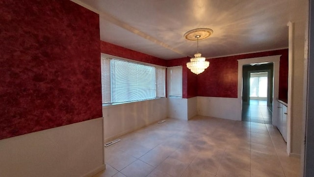 unfurnished room featuring an inviting chandelier and crown molding