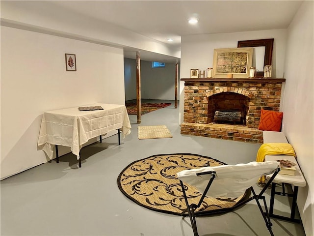 living area with a brick fireplace and concrete floors