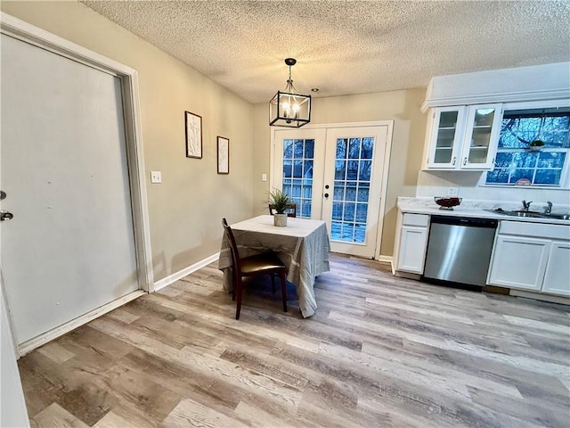 dining space with sink, light hardwood / wood-style flooring, french doors, and a textured ceiling