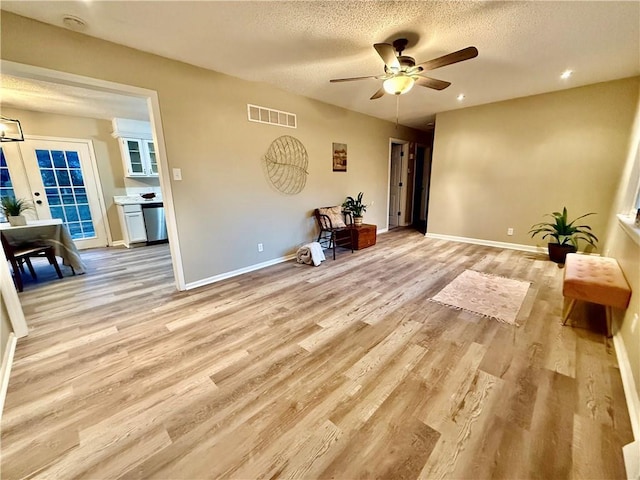 interior space with ceiling fan, a textured ceiling, and light hardwood / wood-style floors