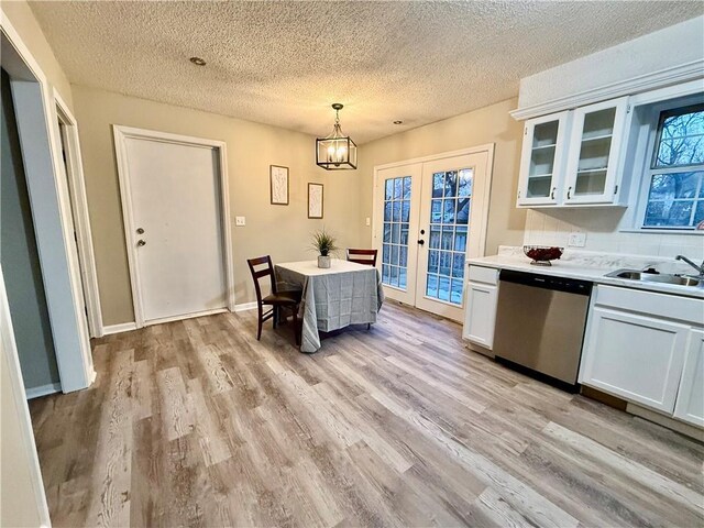 kitchen featuring french doors, sink, stainless steel dishwasher, pendant lighting, and white cabinets