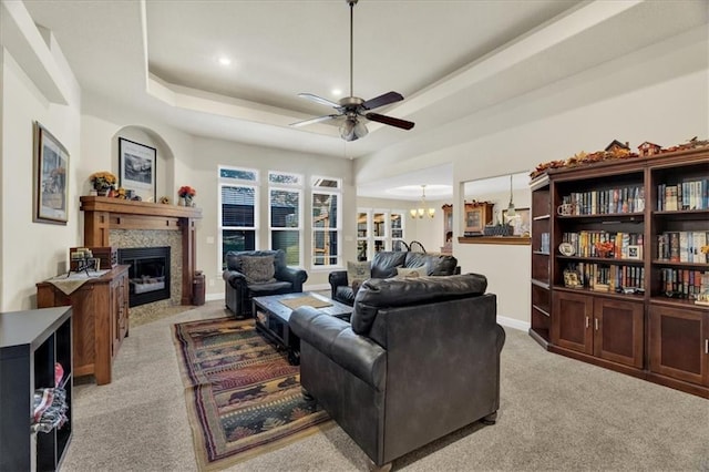 living room featuring ceiling fan with notable chandelier, light carpet, and a tray ceiling