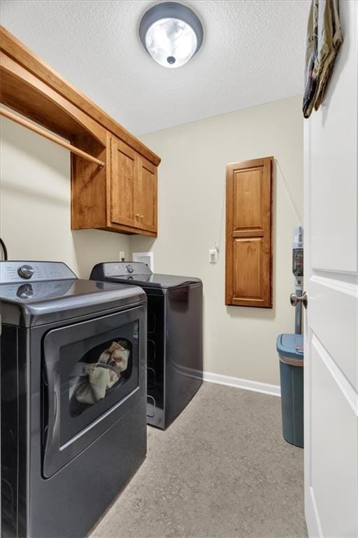 laundry area featuring washer and dryer, a textured ceiling, carpet floors, and cabinets