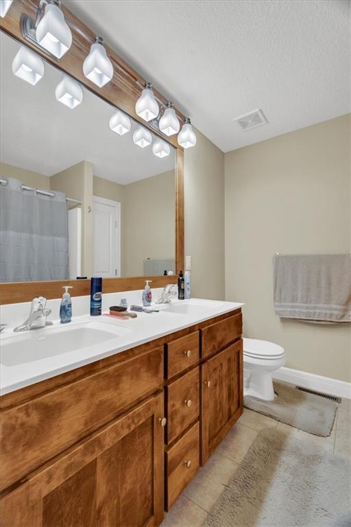 bathroom featuring tile patterned floors, vanity, toilet, and a textured ceiling