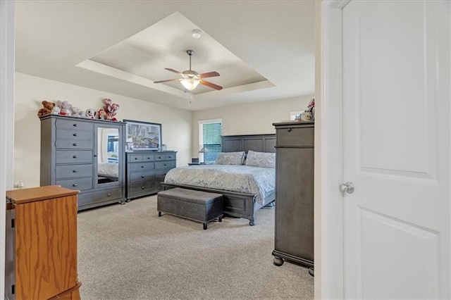 carpeted bedroom featuring a tray ceiling and ceiling fan