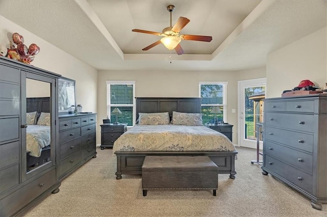 bedroom featuring light carpet, access to outside, a raised ceiling, and ceiling fan