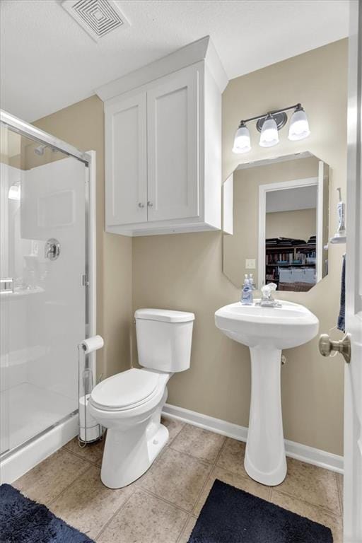 bathroom with tile patterned flooring, toilet, and a shower with shower door