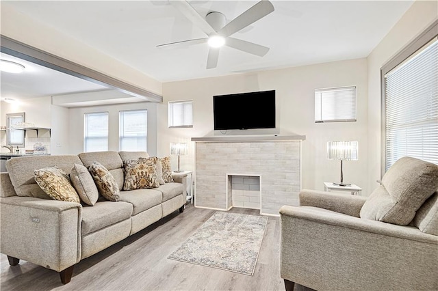 living room with a tile fireplace, light hardwood / wood-style flooring, and ceiling fan