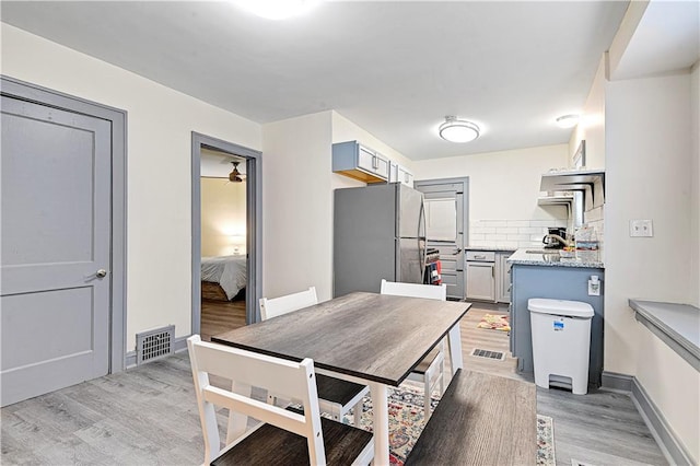 kitchen featuring tasteful backsplash, stainless steel fridge, light hardwood / wood-style flooring, and light stone countertops