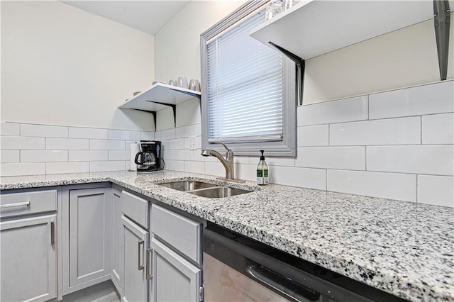 kitchen with decorative backsplash, light stone counters, dishwasher, and sink