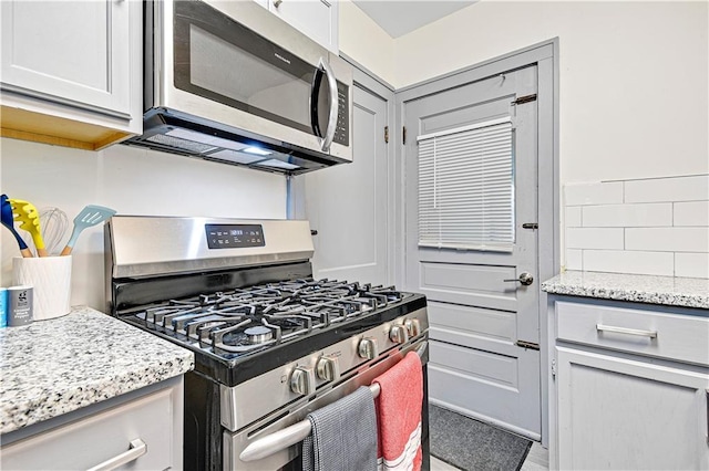 kitchen featuring light stone counters, white cabinetry, and stainless steel appliances