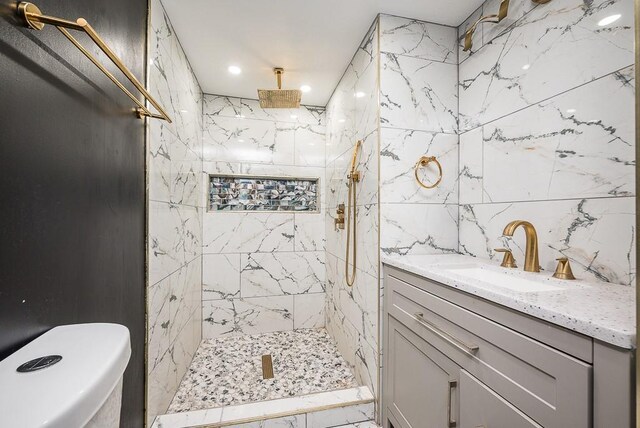 bathroom with vanity, tiled shower, and tile walls