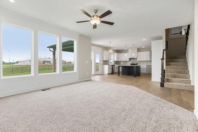 17165 W 164th Ter, Olathe, KS 66062 - unfurnished living room featuring a ceiling fan, plenty of natural light, light colored carpet, stairway, and recessed lighting