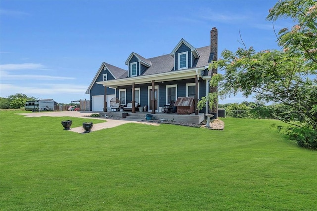 rear view of house featuring a lawn, a garage, and covered porch