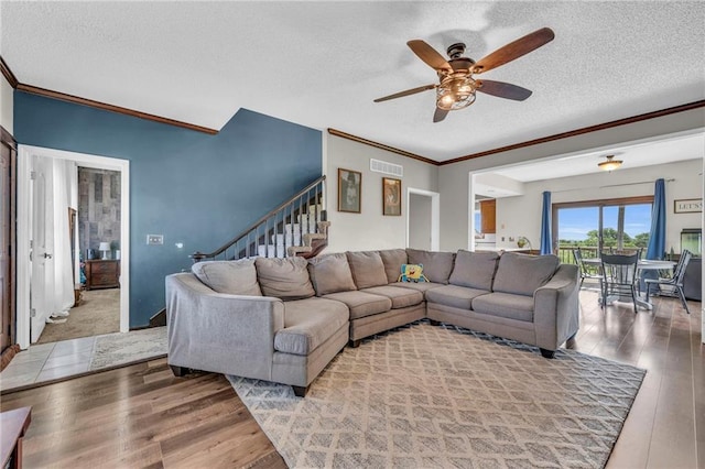 living room with wood-type flooring, a textured ceiling, ceiling fan, and crown molding