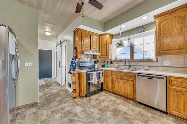 kitchen with ceiling fan, sink, a barn door, backsplash, and appliances with stainless steel finishes