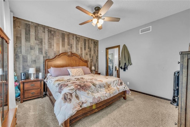 carpeted bedroom featuring wood walls and ceiling fan