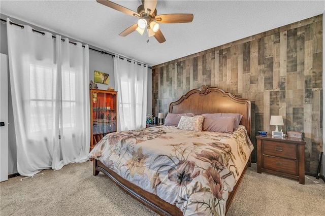 bedroom with a textured ceiling, ceiling fan, wood walls, and light carpet