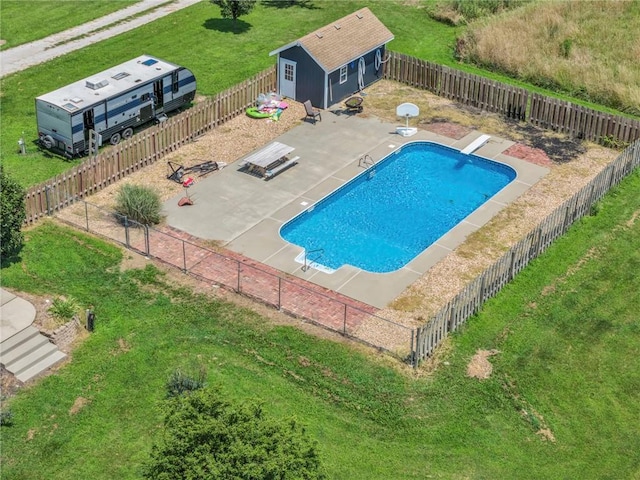 view of swimming pool with a patio area, a diving board, a yard, and an outdoor structure