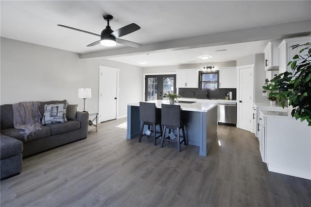 kitchen with white cabinetry, a kitchen island, stainless steel dishwasher, and dark hardwood / wood-style floors